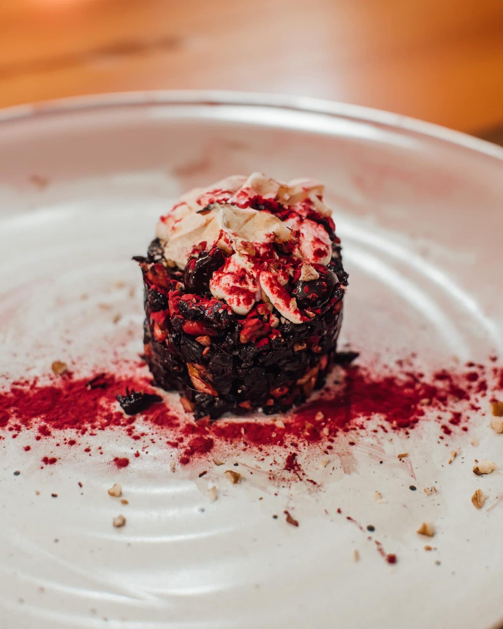 Layered dark dessert with berry dust on a white plate