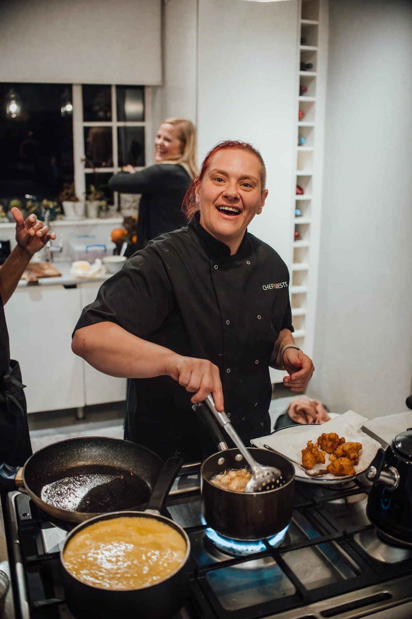 A chef smiling while cooking on a busy stove