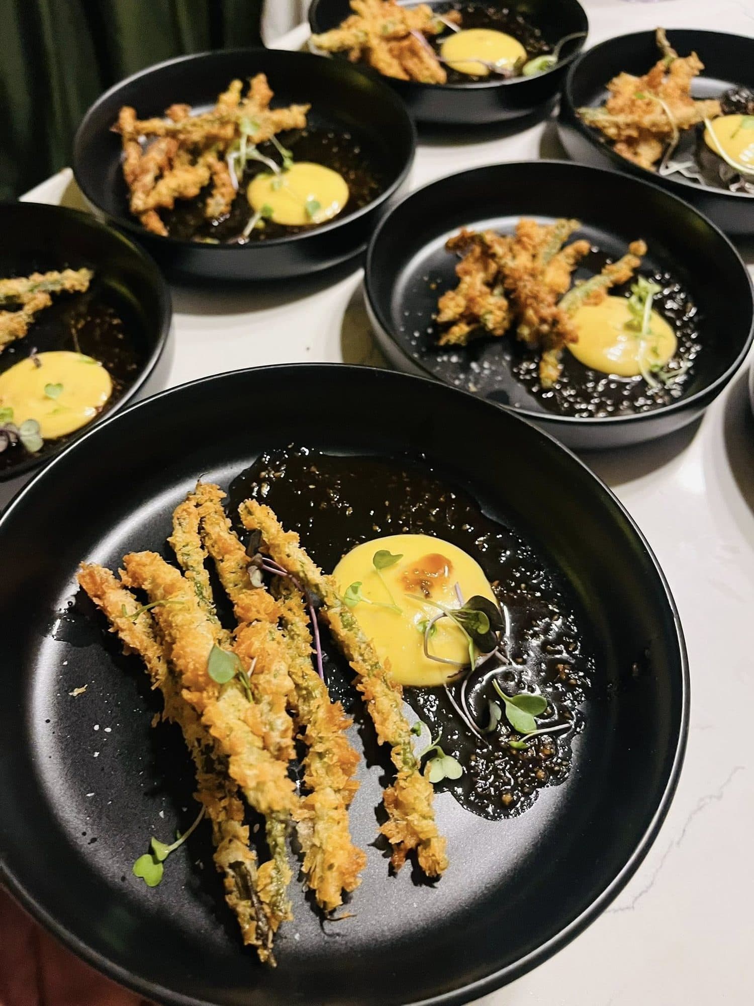 Crisp-fried asparagus with a yellow sauce in dark bowls