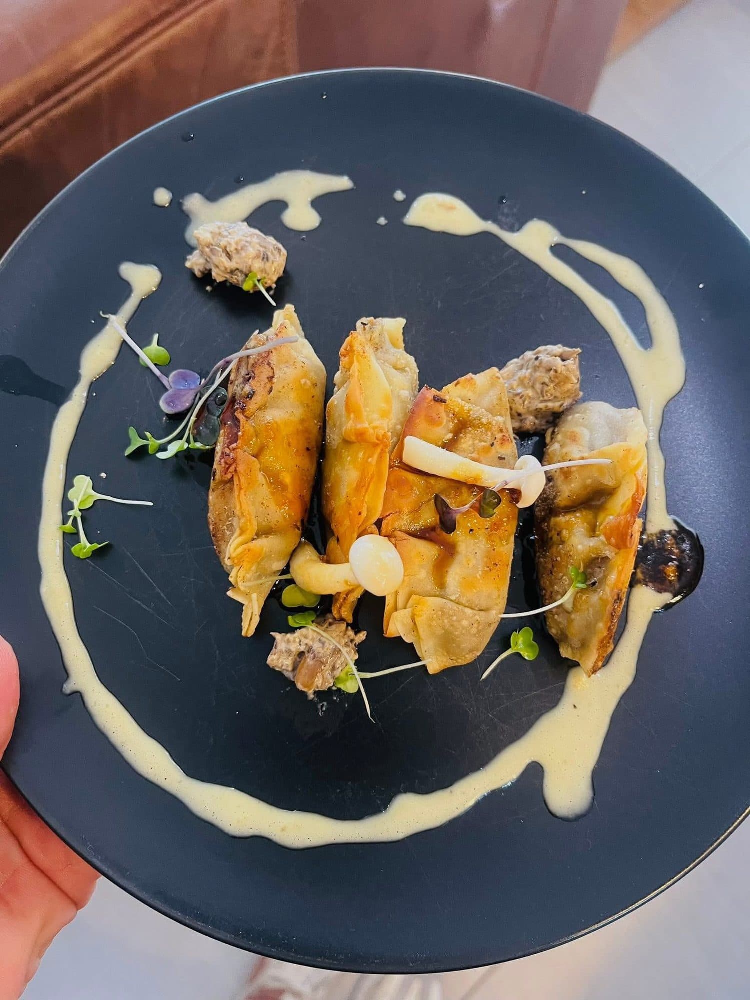 Crisp parcels with a cream sauce swirl on a dark plate