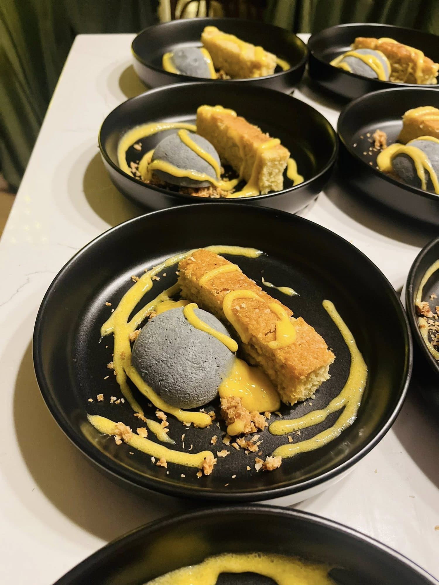 Crisp rolls plated with a bright yellow sauce in dark bowls