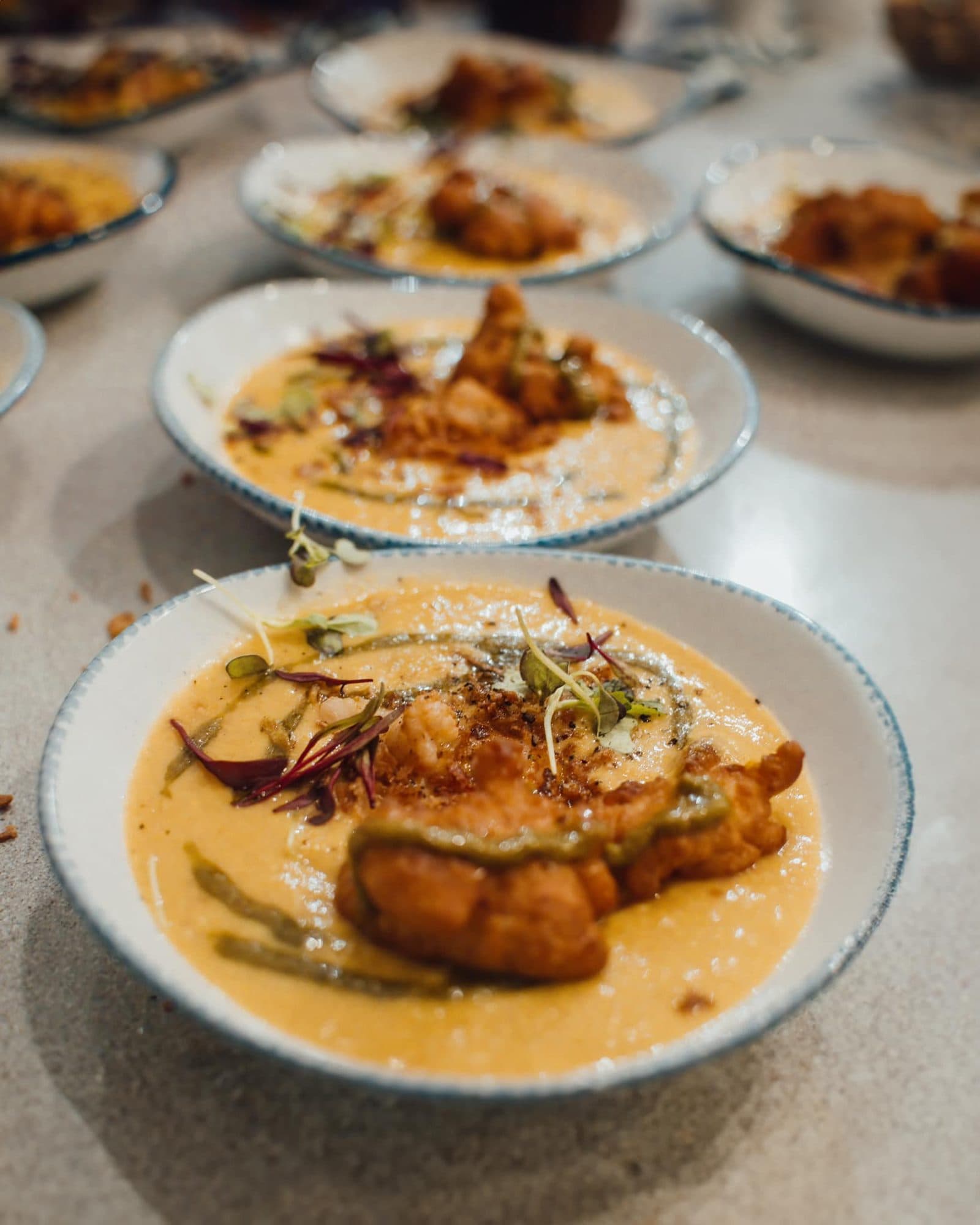 Bowls of fish in a golden curry sauce lined up for service