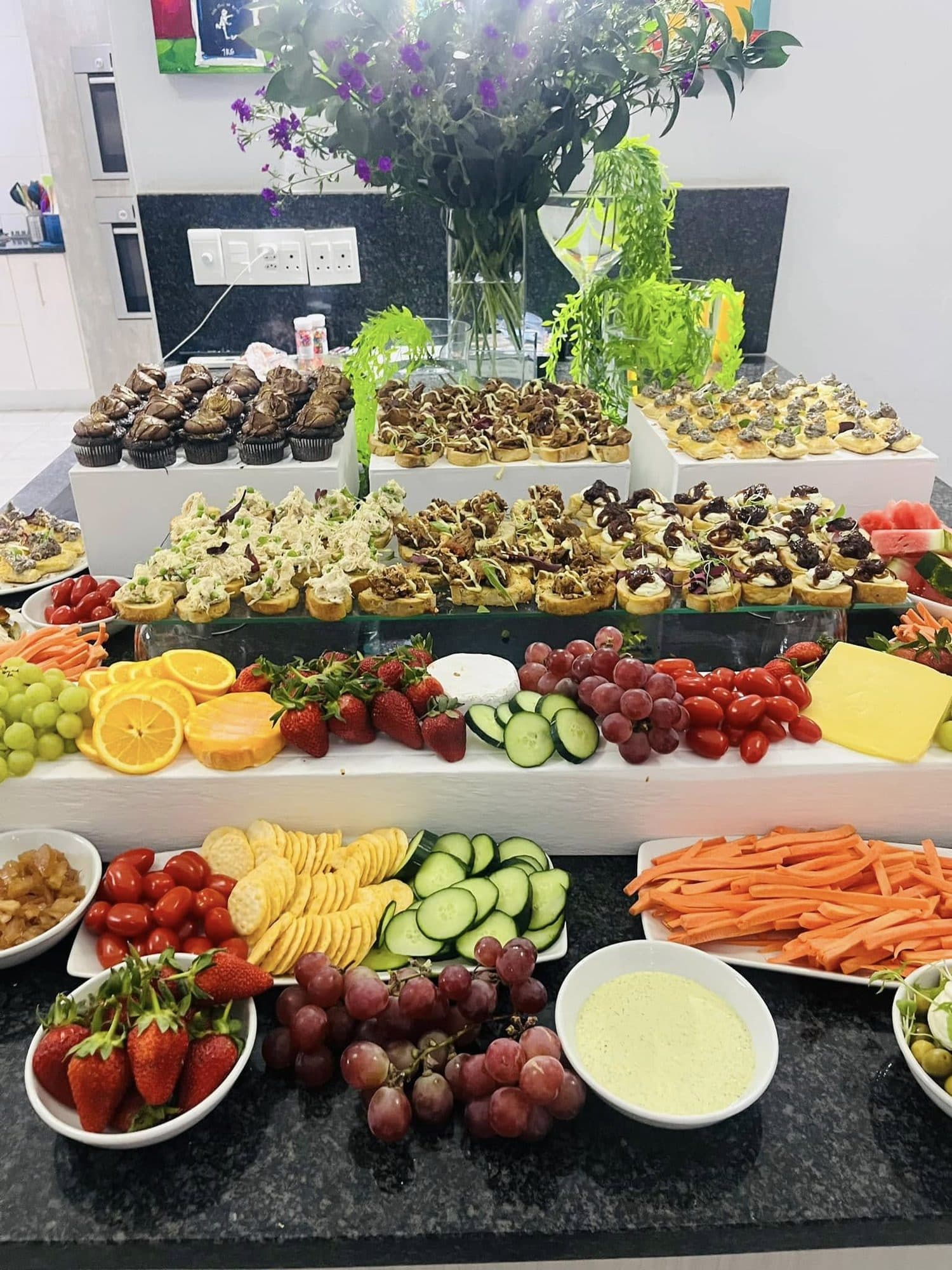 A dessert table of cupcakes, bars and fresh fruit