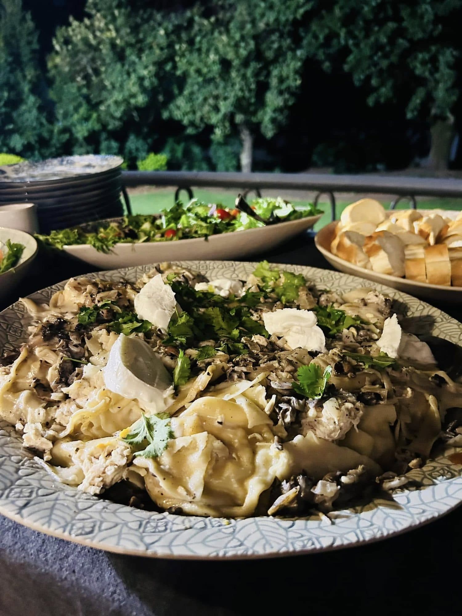 Large platter of pasta with fresh cheese and herbs at an outdoor event