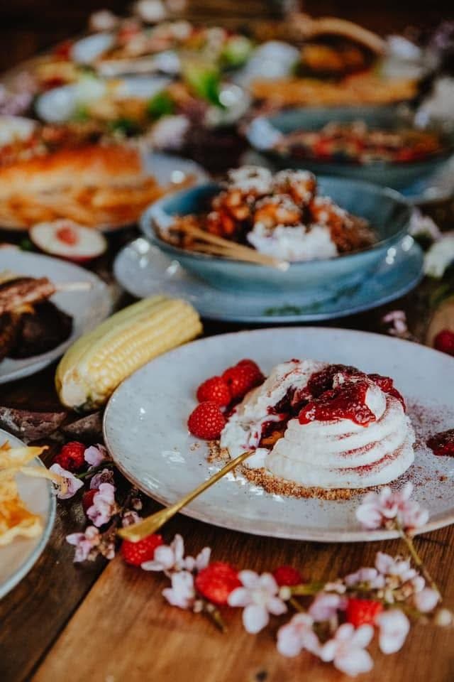Pavlova with fresh strawberries and blossoms on a laden table