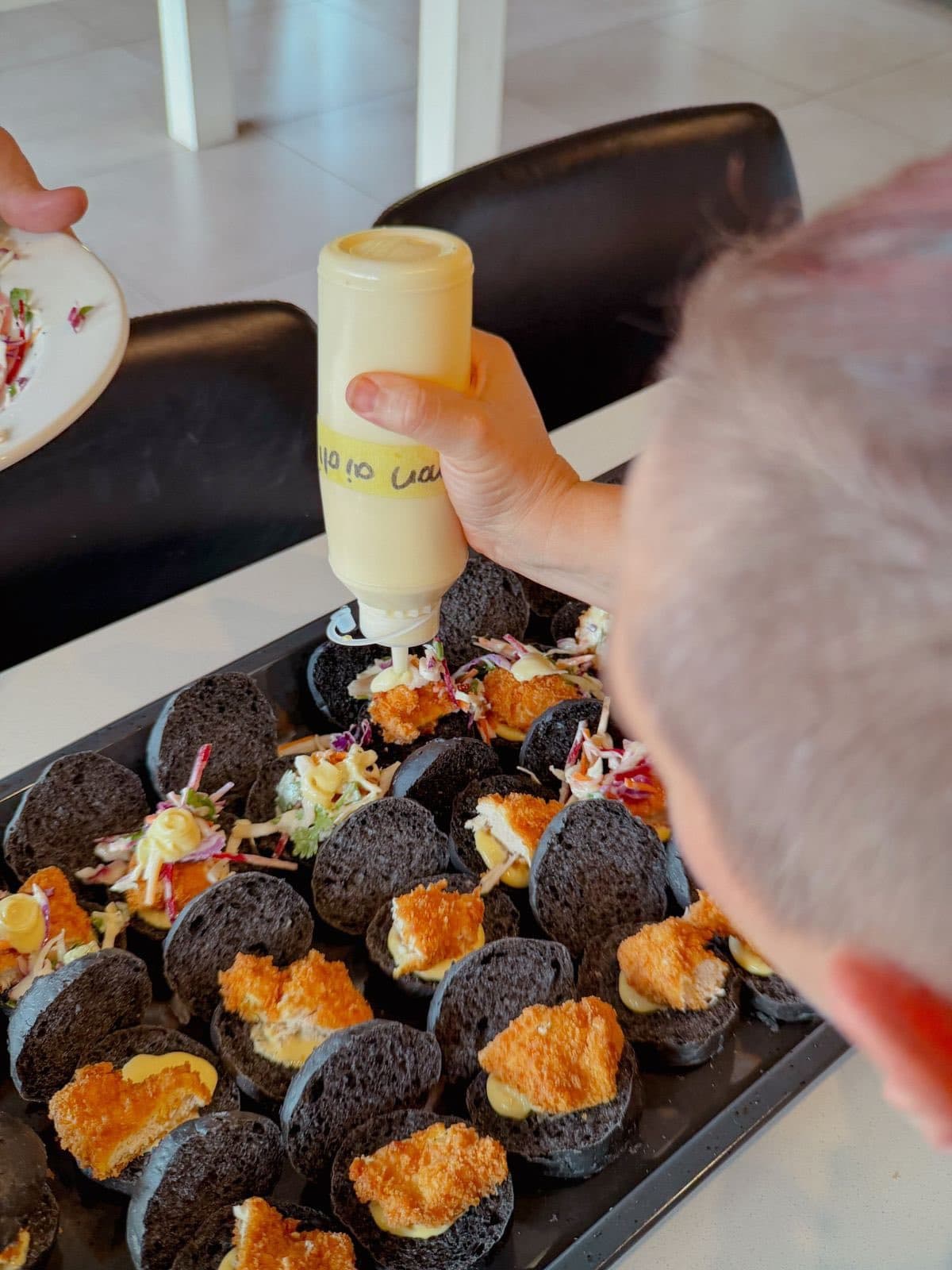 Piping filling into charcoal canapé cups before service