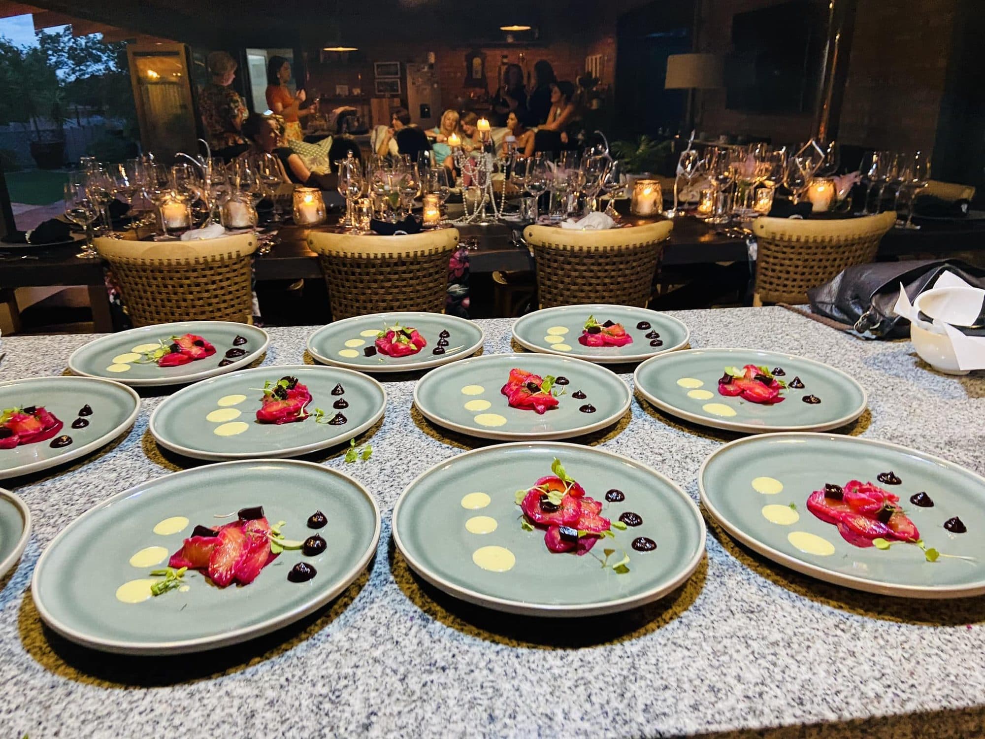 Plated desserts lined up in front of a long, candlelit event table