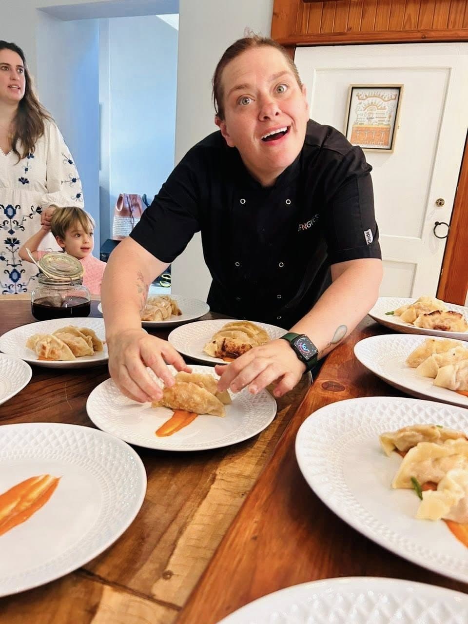 A chef smiling while plating dumplings for a dinner