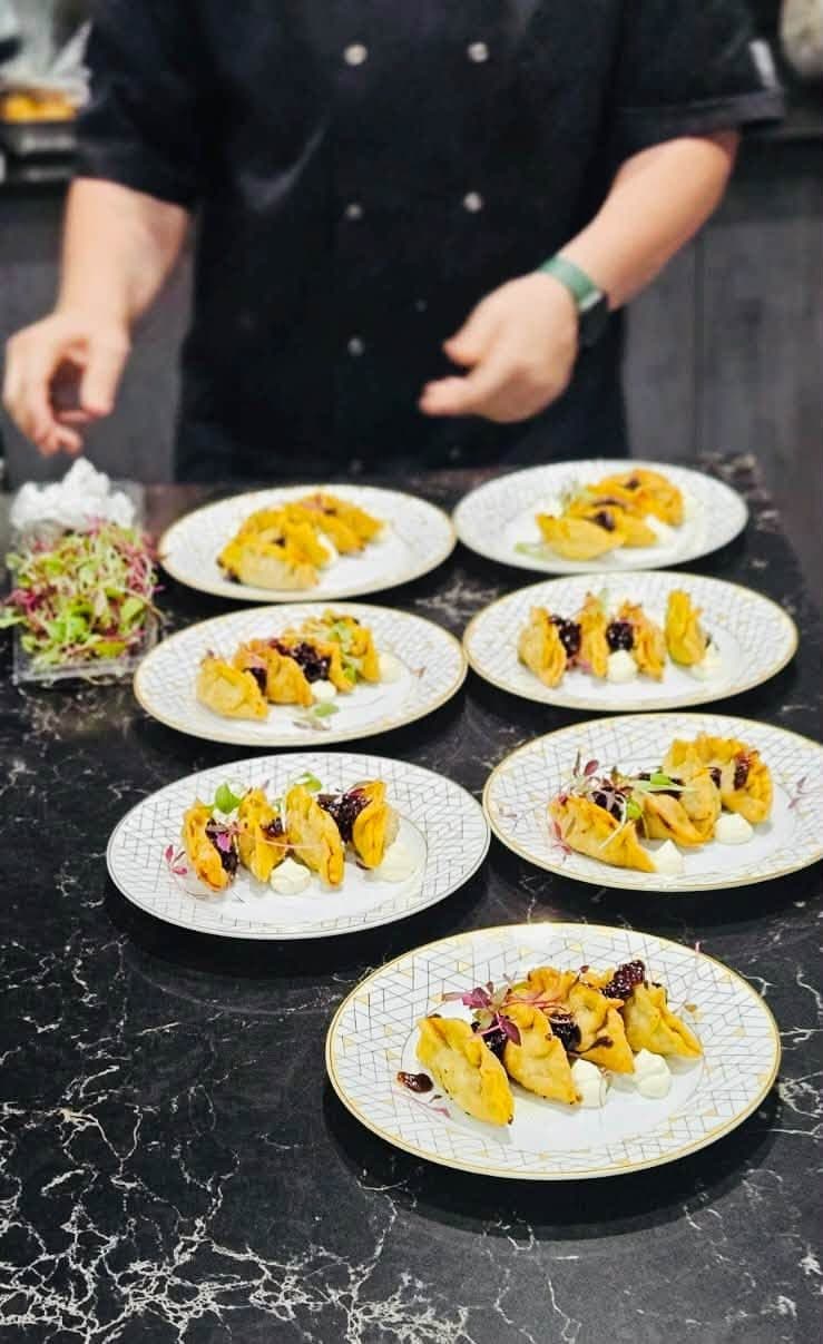 A row of mango dishes being plated on a dark counter