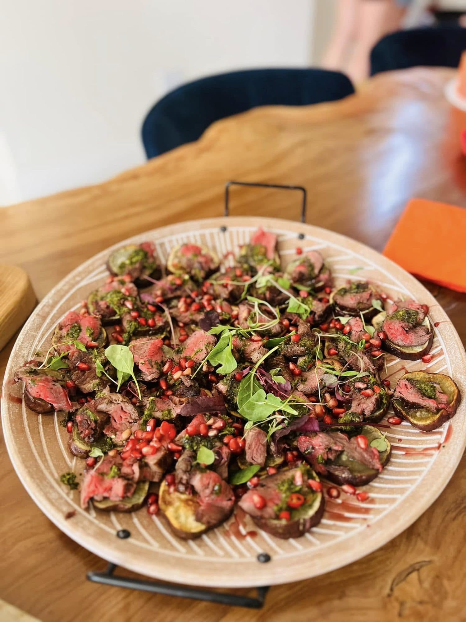 Platter of sliced seared beef with pomegranate and herbs