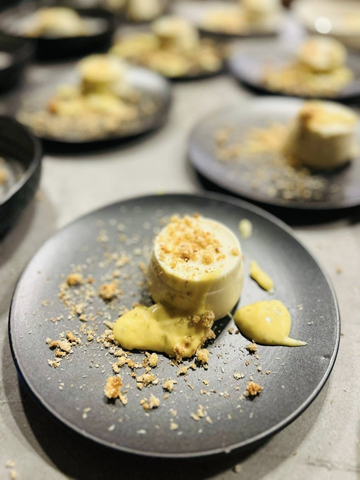 Rows of set cream desserts with crumb, plated for service