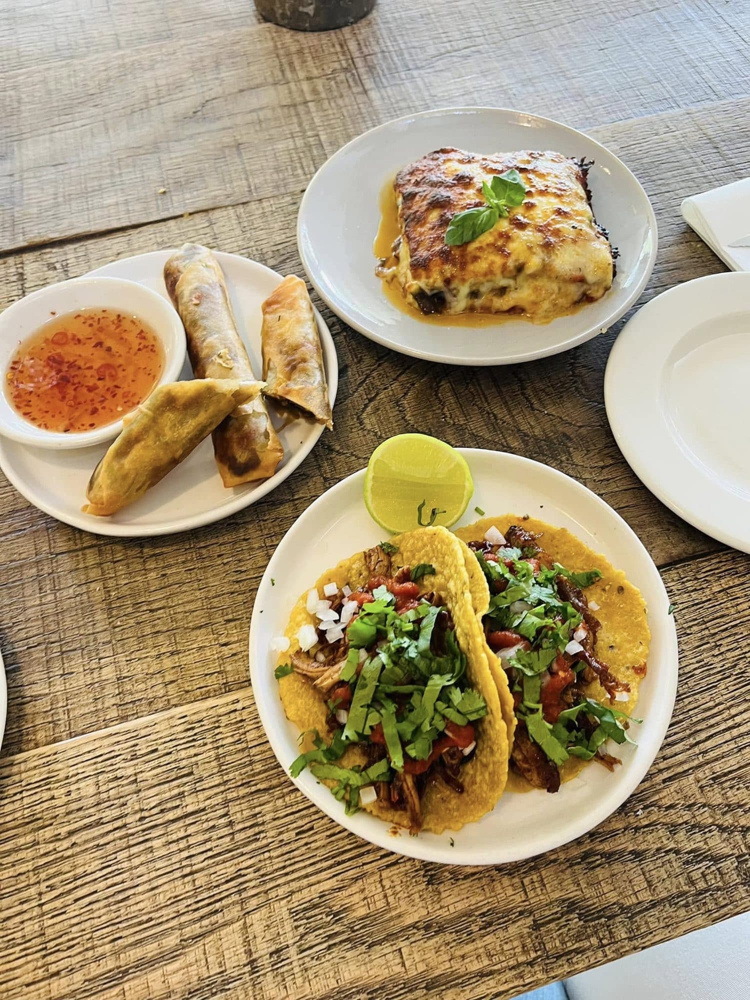 Tacos, spring rolls and a slice of lasagne on rustic plates
