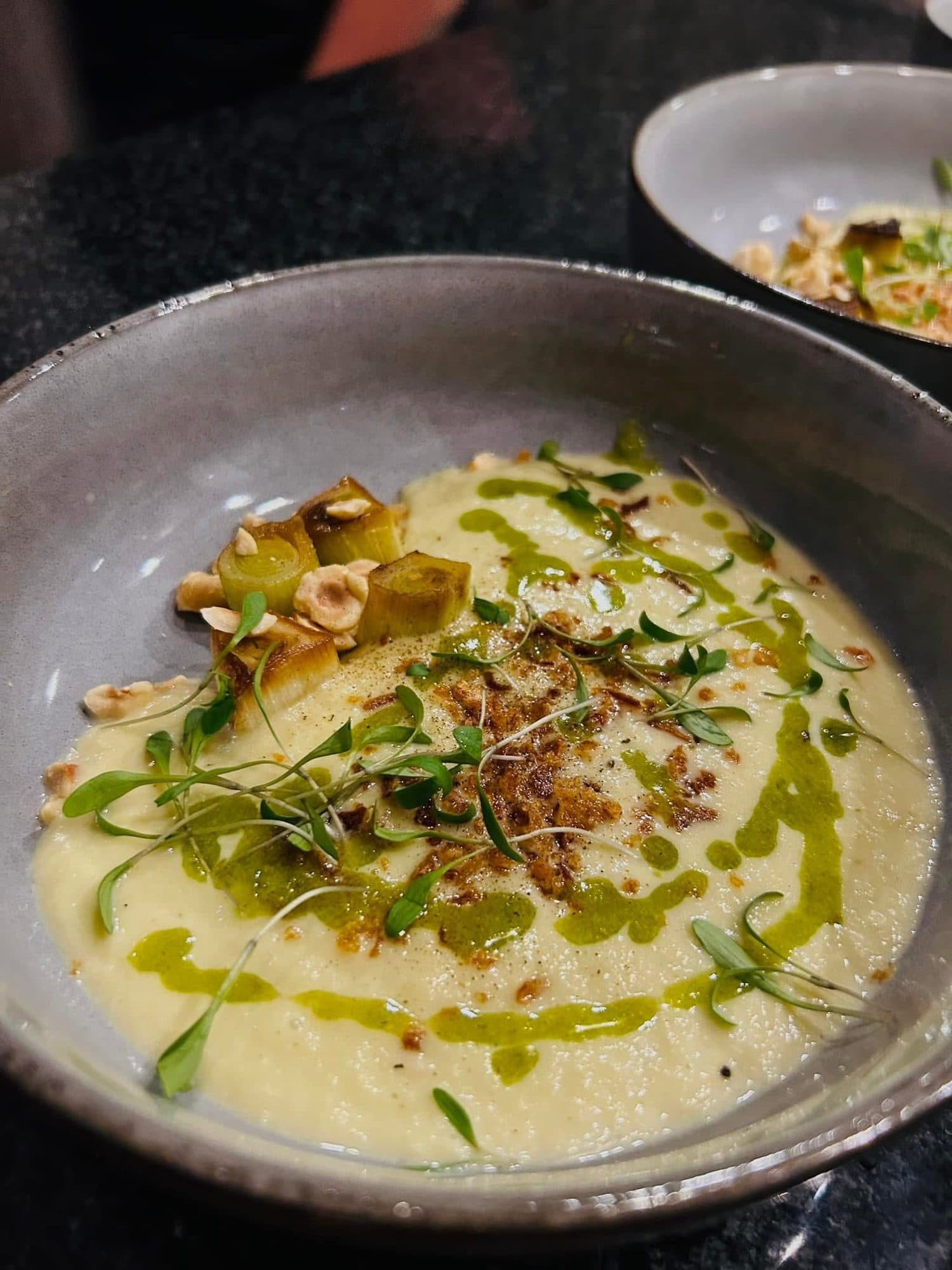 Velvety soup topped with greens, herb oil and toasted crumb