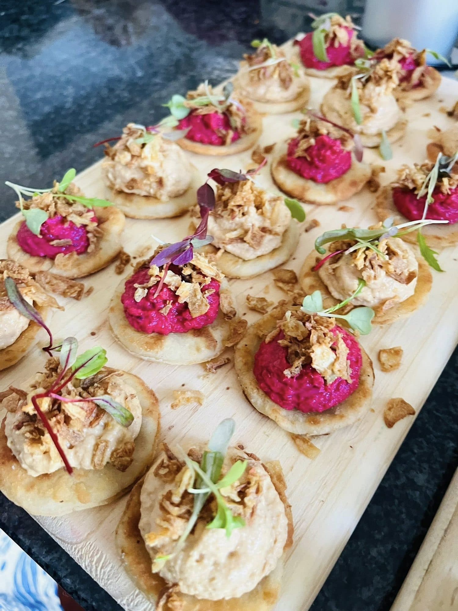 Canapés of beetroot and chickpea spreads on crisp bases