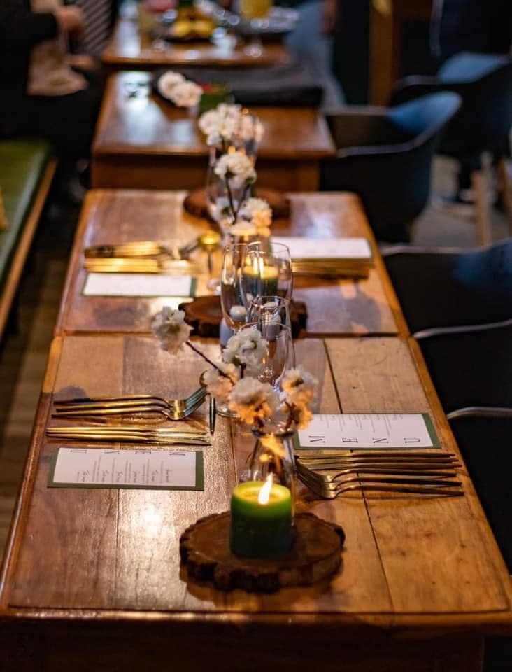 A long wooden table set for dinner with candles and flowers