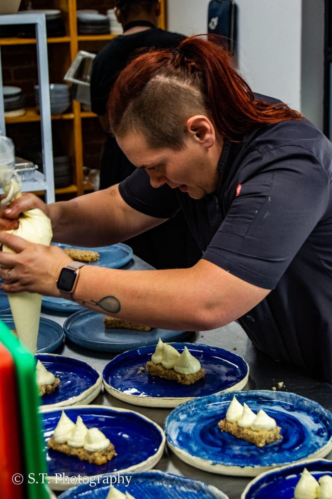 Chef Maradine piping cream onto desserts on blue plates