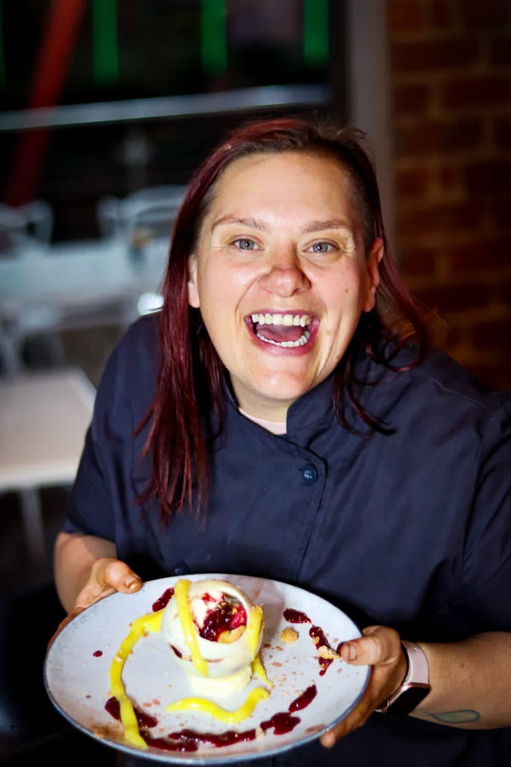 Chef Maradine laughing while holding a plated dessert