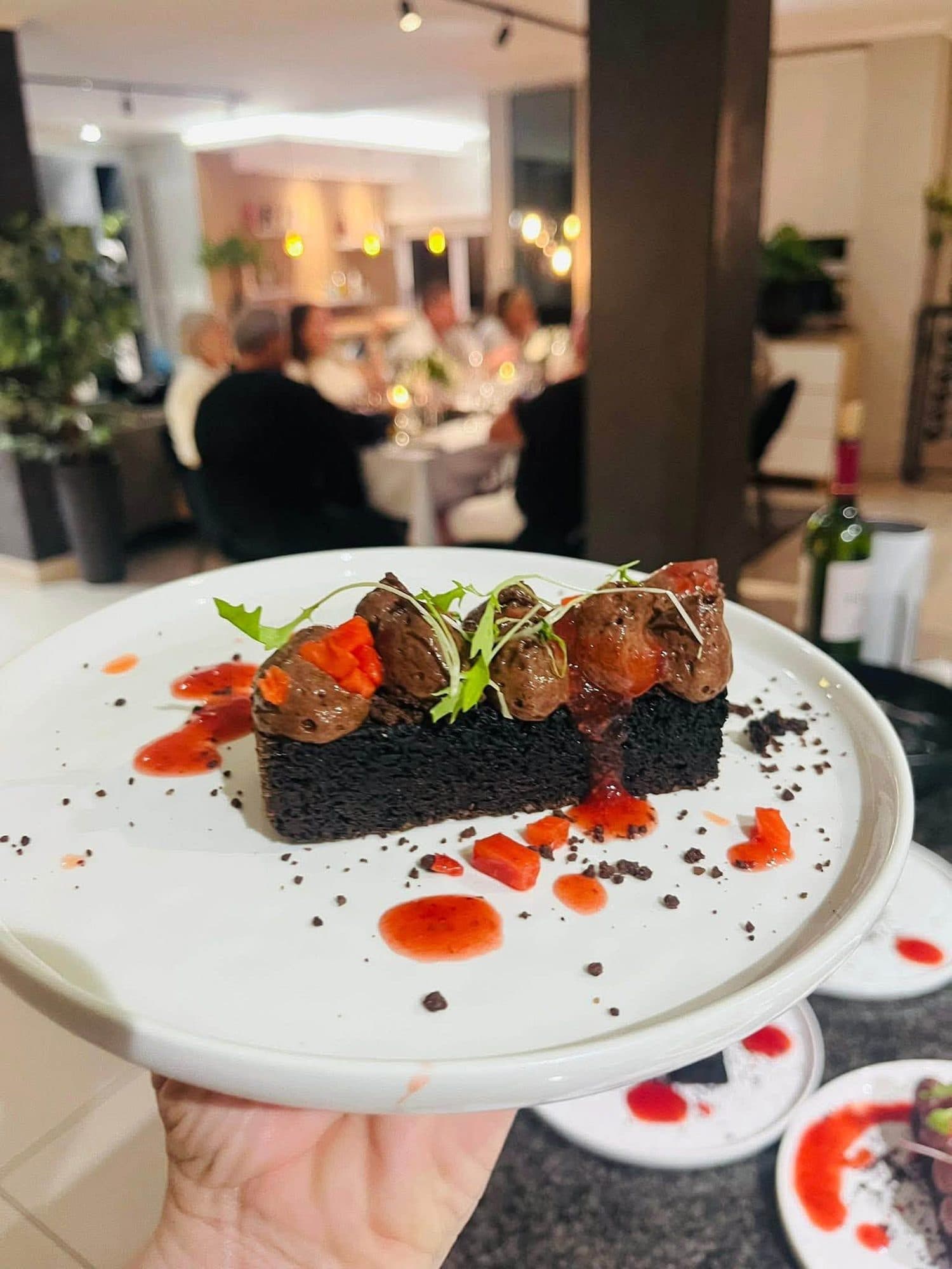 Dark chocolate dessert with red coulis presented at a private dinner