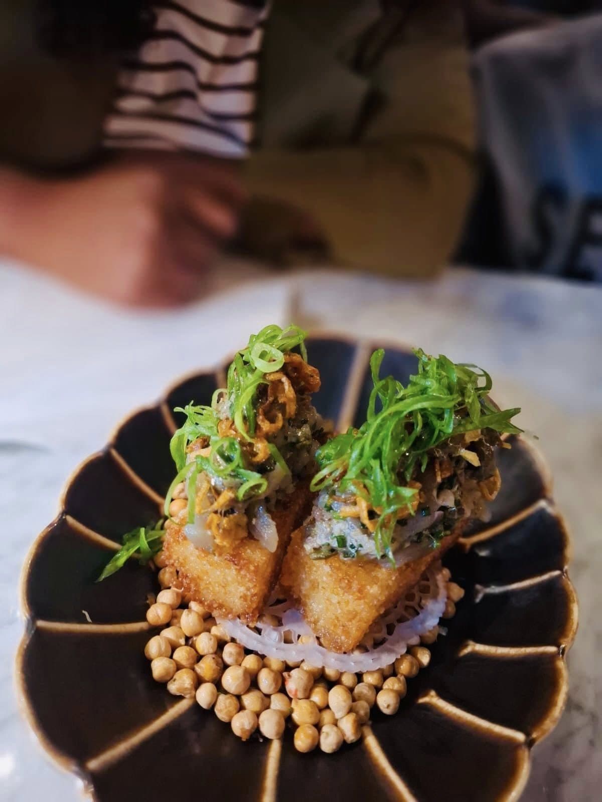 Crisp bites topped with fresh greens on a bed of chickpeas