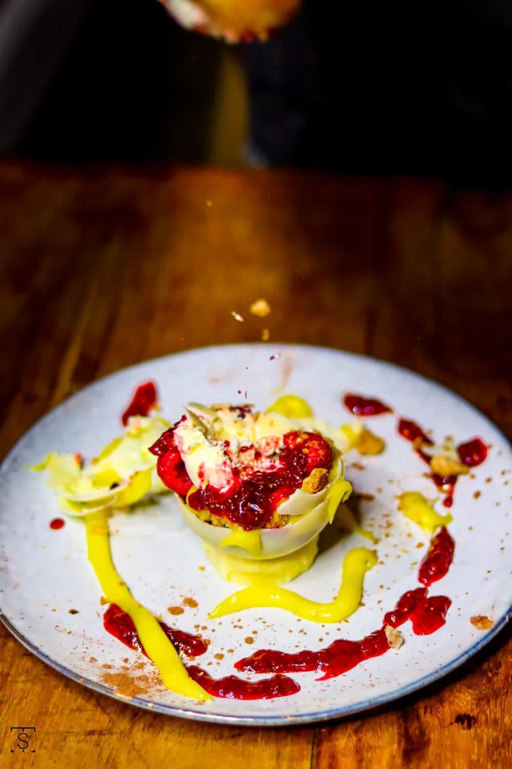 Dessert finished at the table with berry coulis and golden sauce