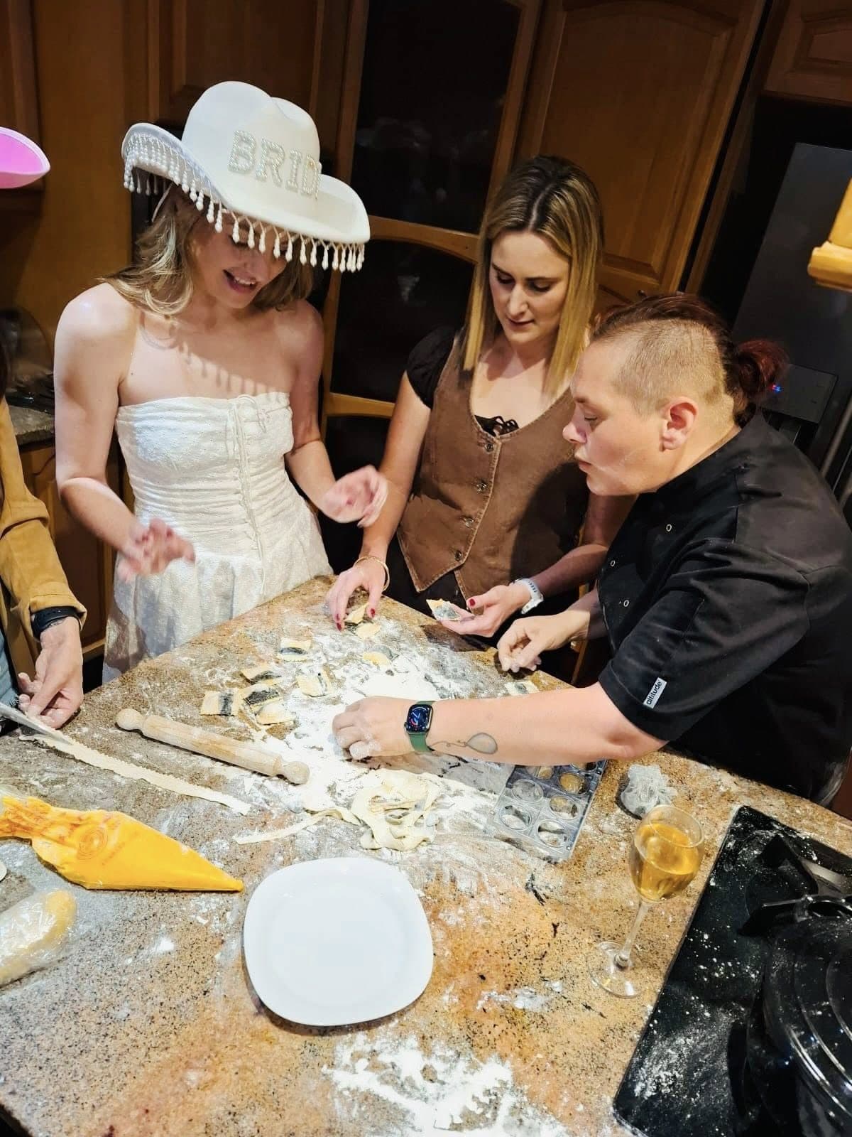 Guests shaping fresh pasta together around a kitchen table