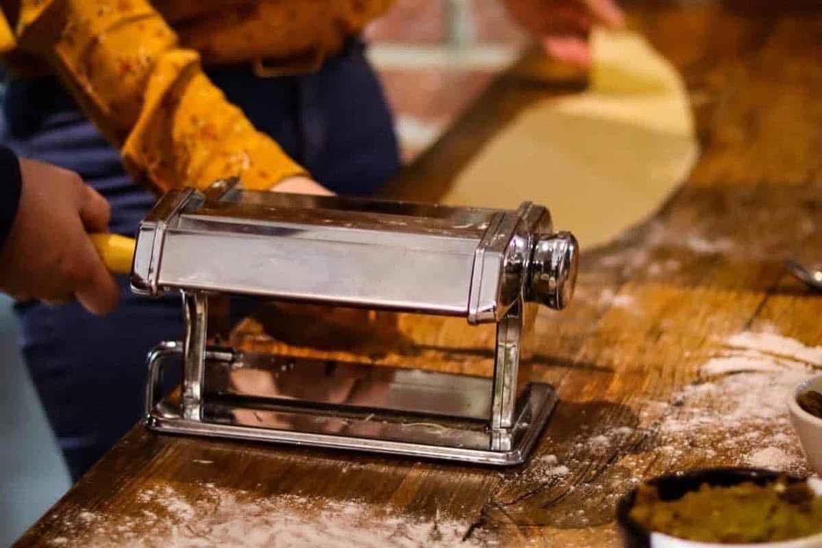 Rolling fresh pasta sheets through a pasta machine
