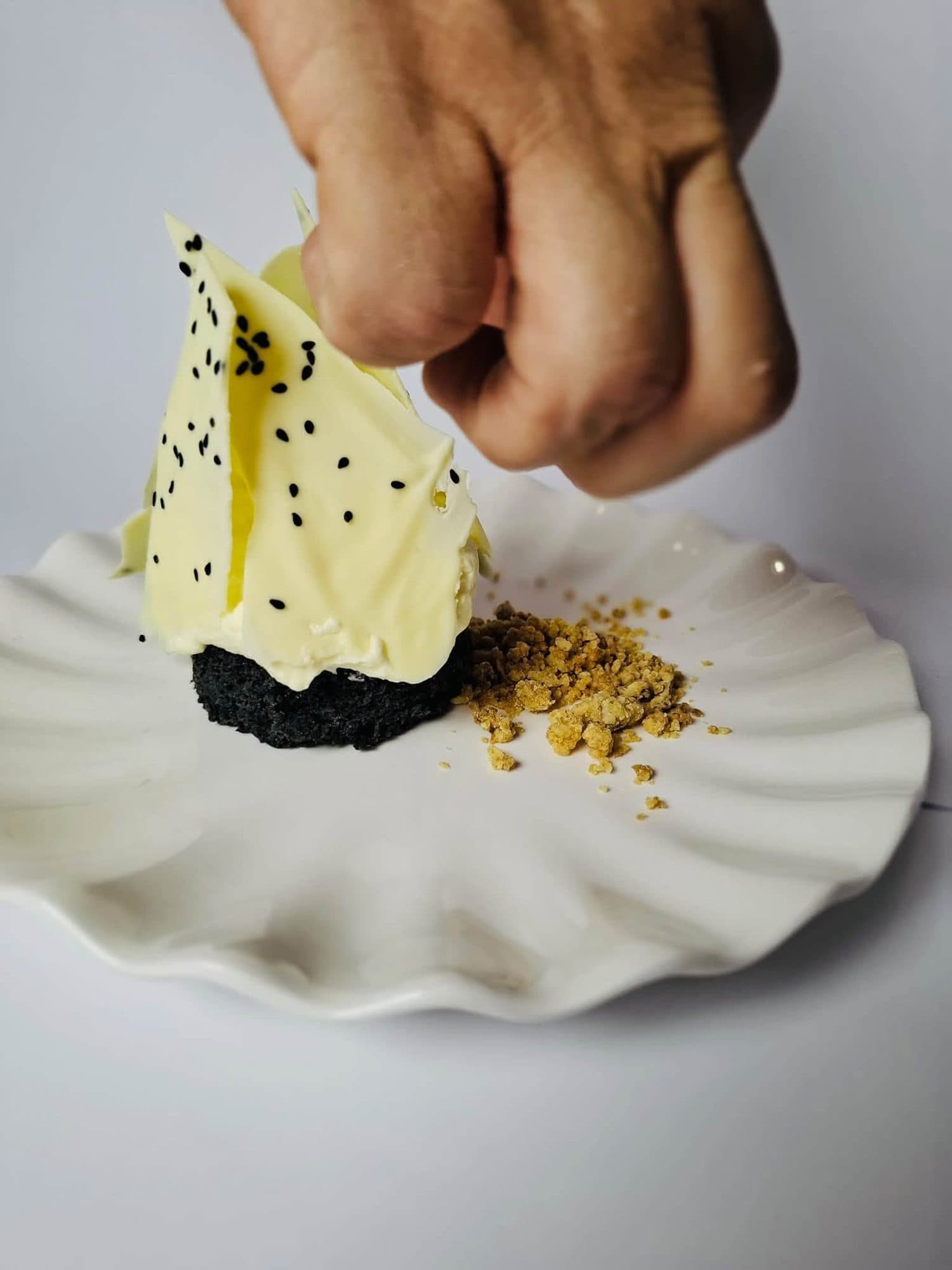 A white chocolate shard dessert being finished with a sprinkle
